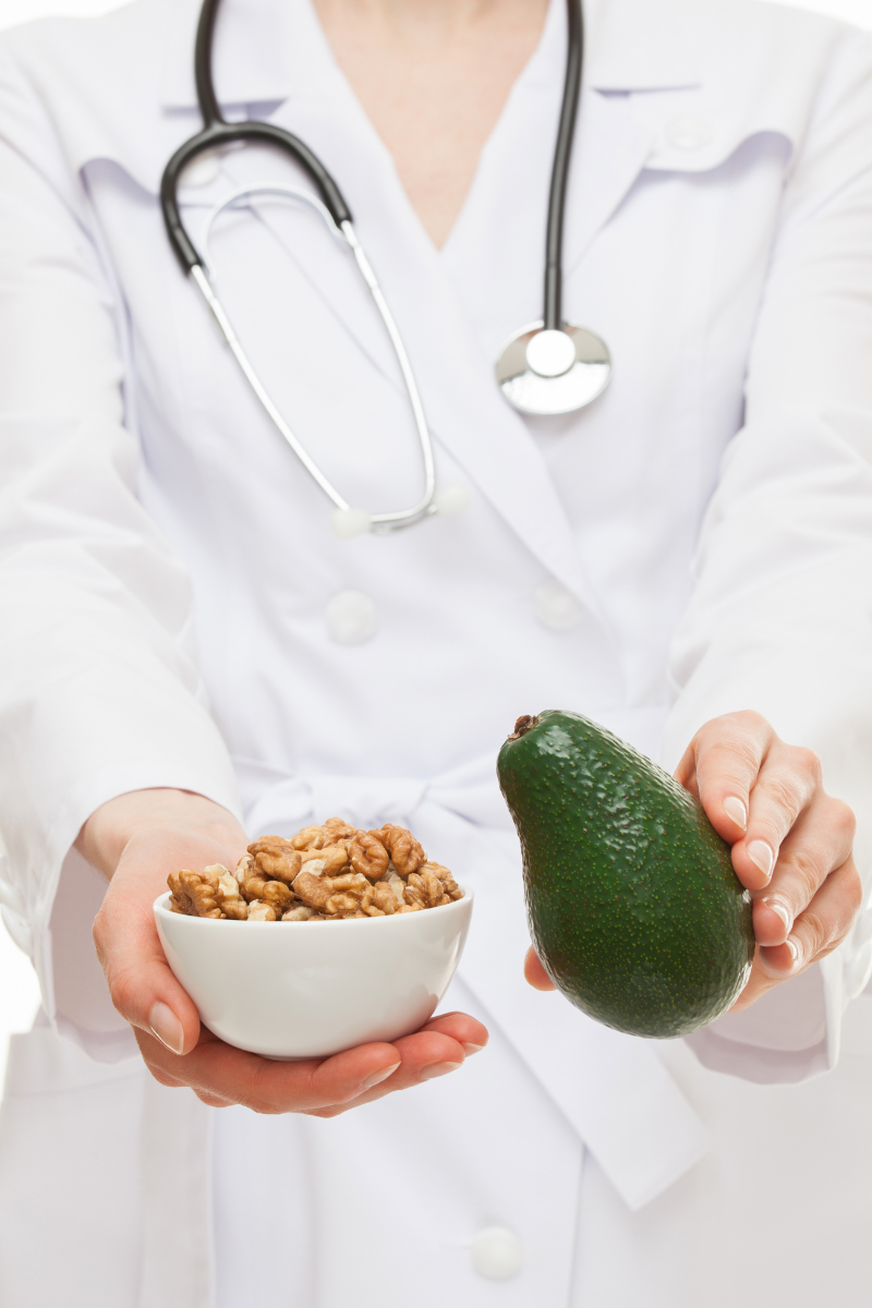 Disordered eating dietitian in white coat holding avocado and walnuts