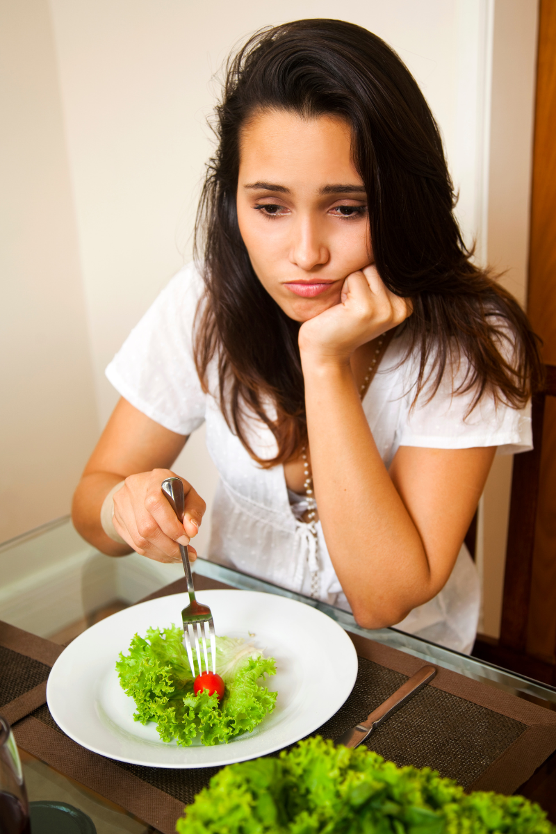 Women sad eating a salad due to long-term dieting.